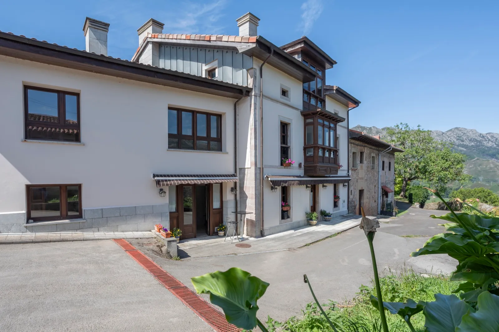 Fachada de La Posada del Vencejo en Alles, con los Picos de Europa al fondo