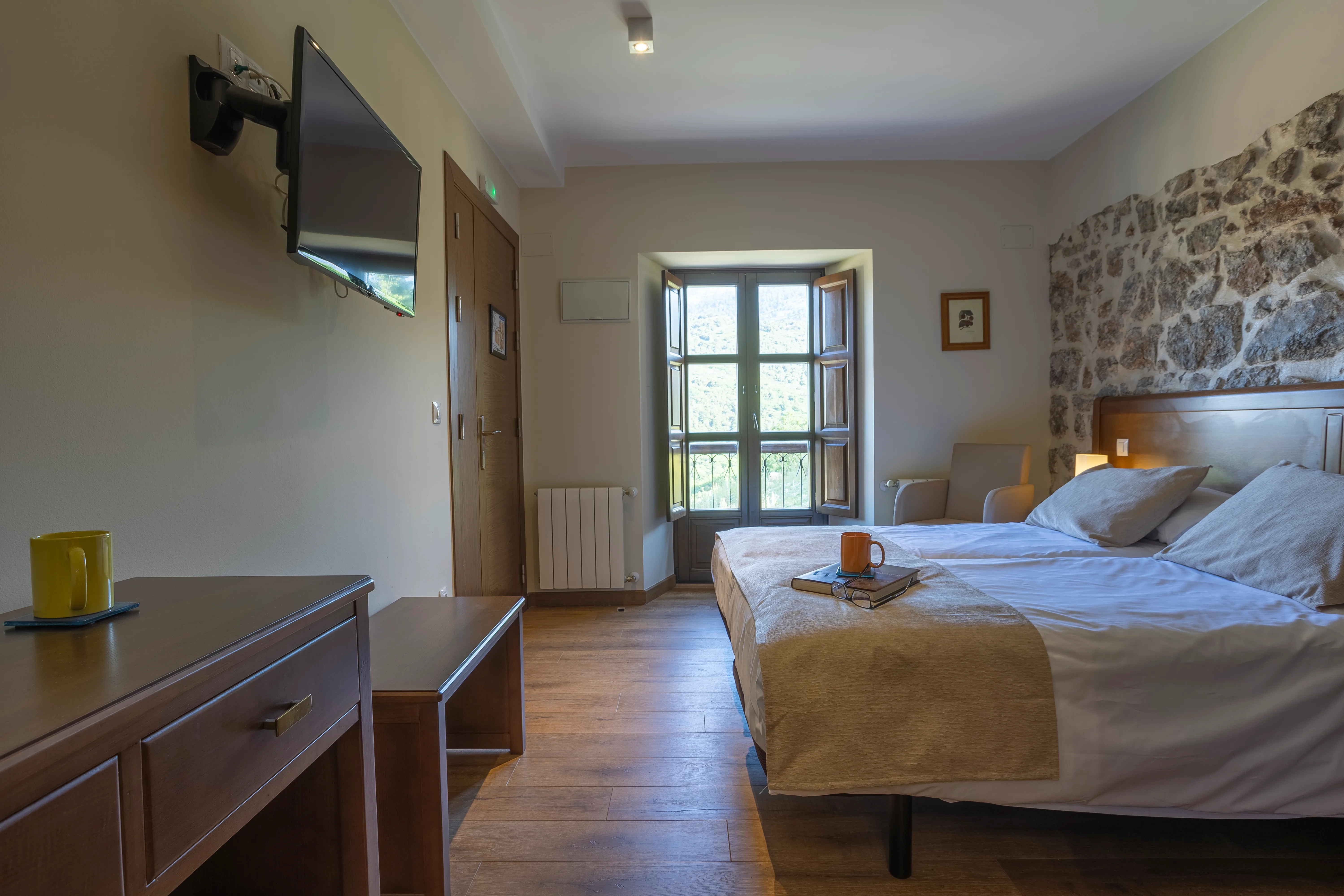 Habitación exterior — detalle de cama con pared de piedra